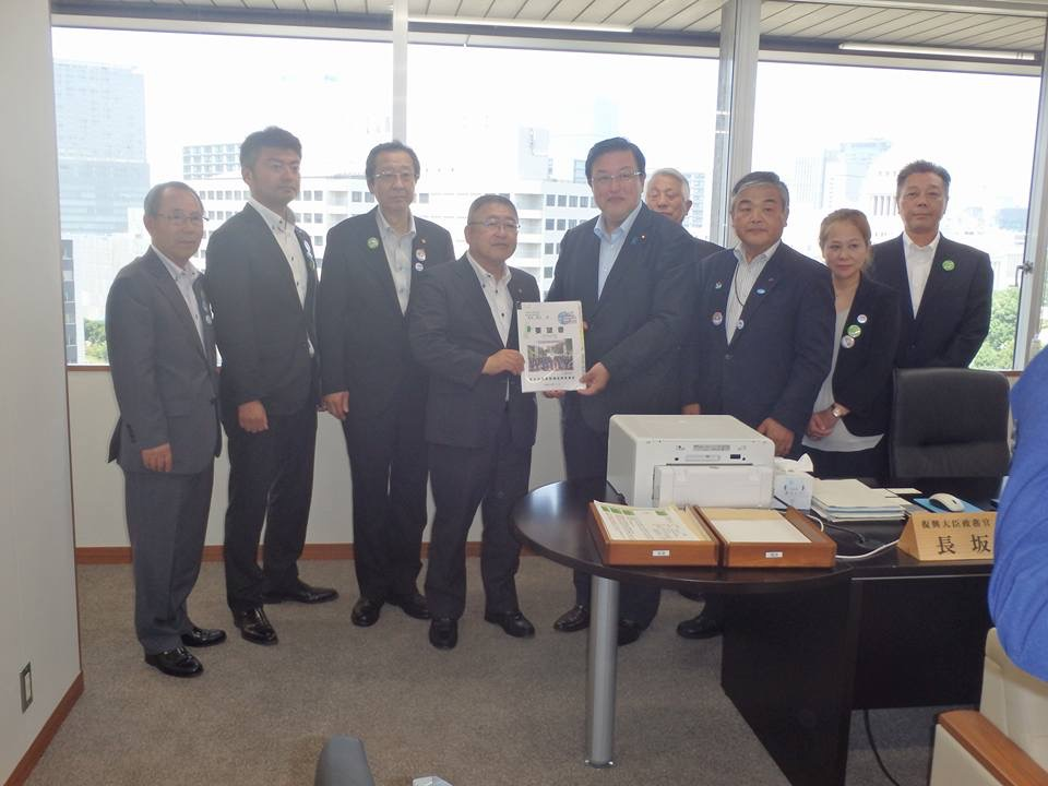 窓際で要望書を一緒に持つ市長と男性と男性6名、女性1名が横一列に並んでいる記念写真