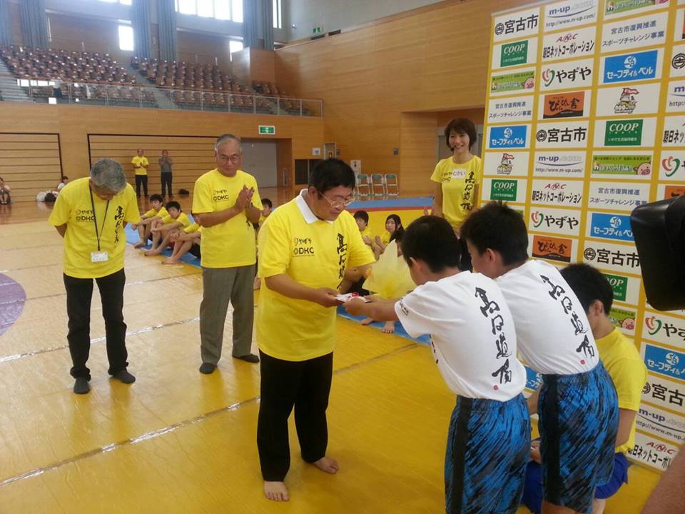 背中に高田道場と書かれたTシャツを着た男の子2人から封筒を受け取る様子の市長の写真