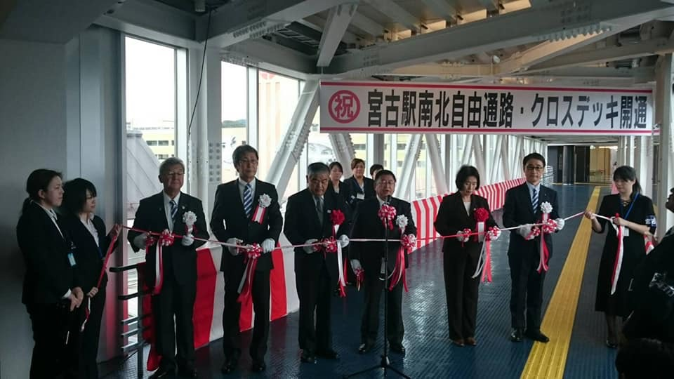 「祝 宮古駅南北自由通路・クロスデッキ開通」と書かれた横断幕の下で、テープカットをする様子の市長と関係者の方々の写真