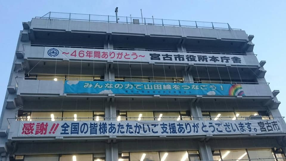 「~46年間ありがとう 宮古市役所本庁舎」「みんなの力で山田線をつなごう!」「感謝!!全国の皆様あたたかいご支援ありがとうございます。宮古市」と書かれた横断幕がベランダに掲げられた建物を写した写真