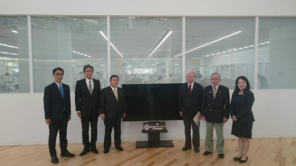 1台のテレビを中心に、市長と男性4名、女性1名が横一列に並んでいる記念写真