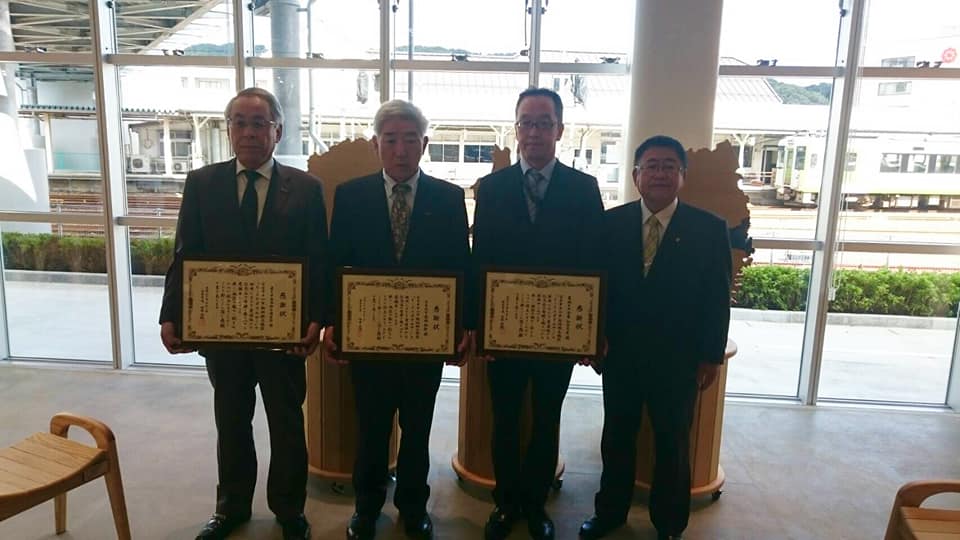 感謝状の額縁を1人1つ持つ3名の男性と、市長が横一列に並んでいる記念写真