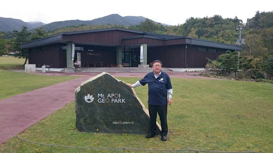 「Mr.APOI GEO PARK」と書かれた石碑に右手をつき、立つ市長を写した写真