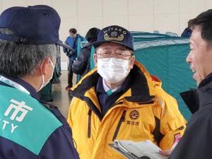 宮古市防護服を着た市長が関係者の人から説明を聞いている避難所設営訓練での写真