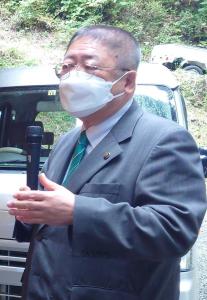 祭りの会場でスーツを着てマスクを付けた市長がマイクを持って話をしている様子の写真