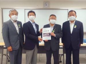 市長と男性が要望書を一緒に持ち、その両側に男性が1名ずつ立って横一列に並んでいる記念写真