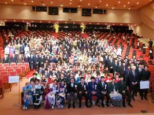 階段状に設置された座席に座り写真に写る着物やスーツを着た新成人の方たちの集合写真