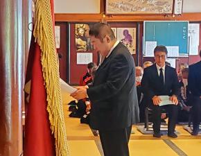 畳が敷かれた部屋で、参列した多くの方々の前で、市長が式辞用紙を開いて読んでいる写真