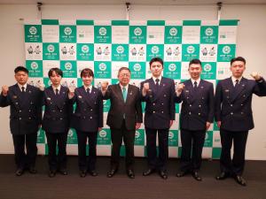 右手の握りこぶしを胸の前に掲げポーズを決める新採用消防職員6名と市長が並んでいる写真