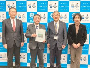 提言書を持つ市長と、関係者の方々3名がバックパネルの前で横一列に並んでいる写真
