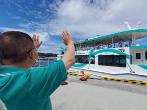 港を出航する宮古うみねこ丸に向かって両手を振る市長を後ろから写した写真