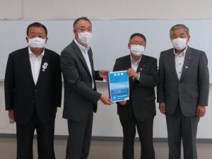 市長と男性が要望書を一緒に持ち、その両側に男性が1名ずつ立って横一列に並んでいる記念写真