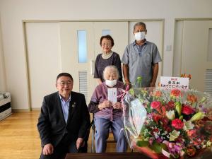 市内最高齢者である久保田イチさんと市長が前列に座って並び、後列にご家族の方2名が立って写る記念写真