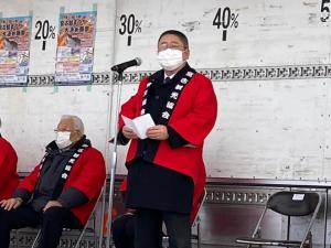 赤色の法被を着た市長がマイクスタンドの前で挨拶を行っている、元祖宮古鮭まつりの様子の写真