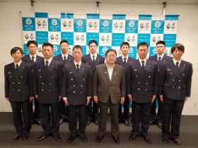 宮古市のバックボードの前で訓練を終えた制服姿の消防職員10人が市長と2列に整列して記念撮影をしている写真