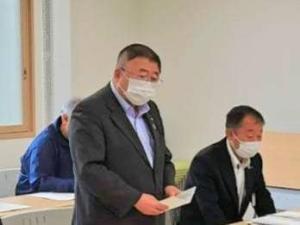 立って資料を両手に持ち話している様子の市長と、その隣で椅子に座り机の上に置かれた資料を見つめている様子の男性の写真