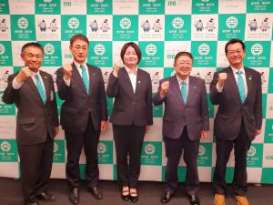 バックパネルの前に、前田結美さんを中心にして市長、副市長、他2名が並び、右手でガッツポーズをしている写真