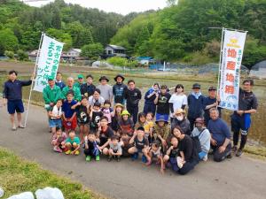 田んぼわきの道路で記念写真をする参加者たちの写真
