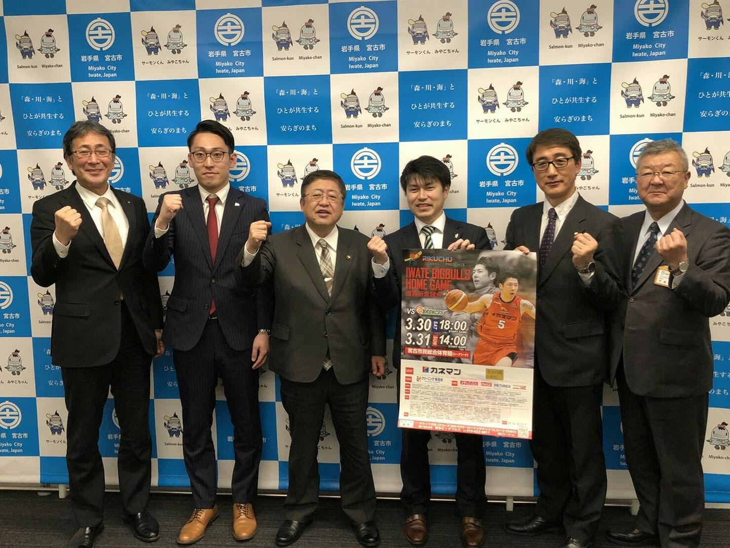 バックパネルの前で市長を中心に株式会社岩手ビッグブルズの水野哲志代表取締役社長、伊藤康輔取締役、岩手ビッグブルズクリスタルパートナーの陸中建設株式会社伊藤峻代表取締役専務と関係者の男性3名が横一列に並んでいる記念写真