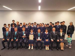 市長が目録、女子生徒が賞状をそれぞれ持ち、生徒会の皆さん、関係者の方々が集合して撮影した写真
