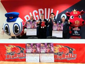 BIGBULLSと書かれた応援幕の前で岩手ビッグブルズと三陸鉄道のマスコットの間に市長と岩手ビッグブルズの水野哲志代表取締役社長、三陸鉄道の石川義晃代表取締役社長 、大槌町の平野公三町長が「対ベルテック静岡戦」のポスターを持ち、並んで撮影した写真