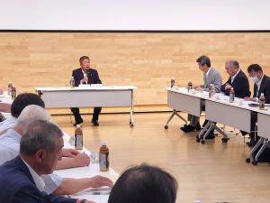 対面式に設置された長机に座っている参加者の方々の前の席で市長が座って話をしている写真
