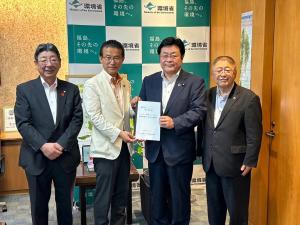 環境賞にて、西村環境大臣、山田市長、佐藤町長、山本市長の4人が並び、中央の2名が要望書を持っている写真