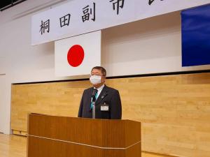 「桐田副市長就任式」と開かれた横断幕が掲げられた檀上に立つ市長が挨拶を述べている様子の写真
