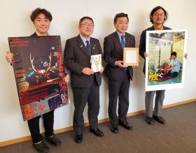 市長と三陸鉄道・中村社長がサントリー地域文化賞の盾を持ち、芸術祭関係者2人が三陸国際芸術祭のポスターを持ち、並んで撮影した写真