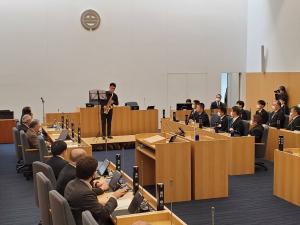 宮古市議会議場中央でサクソフォーンを演奏している大村光介さんと演奏を聴いている市議会議員と市幹部職員の写真