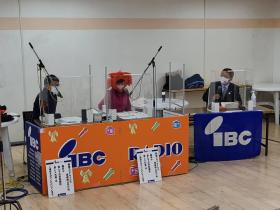 IBCと書かれた幕が貼られた、それぞれの席で神山浩樹アナウンサー、風見好栄アナウンサー、市長が話をしている写真