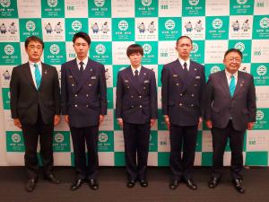 バックパネルの前で制服を着た消防職員3名が中央に並びその右側に市長、左側に男性が並んでいる写真