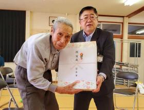 市長が関向繁男さんに市からのお祝いの記念品を渡している写真