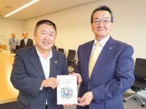 市長と新居克洋会長が2名で寄贈した本を持っている写真
