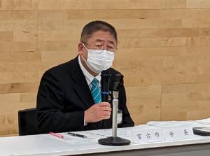 椅子に座り右手にマイクを持って話している様子の市長の写真