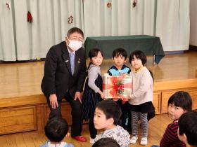 他の園児たちが見ている中、寄贈した積み木を3人の園児が持ち、市長と並んで撮影した写真