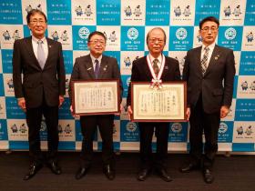 受章のメダルをかけ、賞状を持った津田重雄さんと賞状を持った市長と市職員2人が並んで撮影した写真
