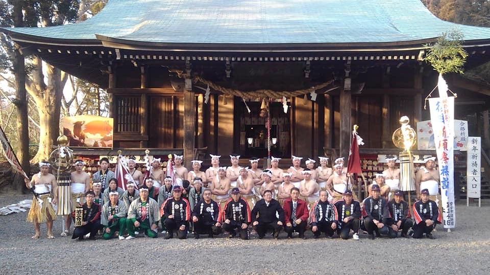 神社の拝殿の前で、復興裸詣祈願祭に参加した胴巻の上に注連縄をつけて草鞋を履き、鉢巻を額の中央で結んだ下帯姿の団員や法被を着た団員、中央前列に市長が座っている集合写真