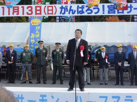 舞台の上で市長がマイクの前で挨拶している写真