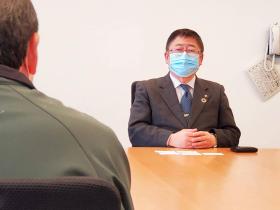 市長が椅子に座り、サケの卵を提供していただいた大仙市の方と対面して話をしている写真