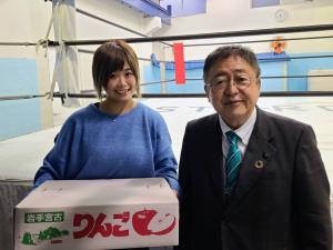 道場のリングの前で、宮古産のりんごの箱を持った女子プロレスラーのMIRAIさんと市長が並んでいる写真