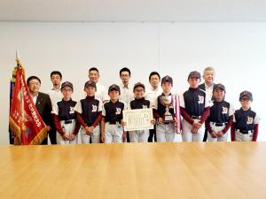 優勝旗を持った市長と賞状とトロフィーを持ったユニフォーム姿の宮古ヤングパワーズの8人児童たちと関係者の方々が集合して撮影した写真