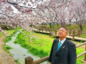 満開の桜の下で、顔を上に向け桜を見ている様子の市長の写真