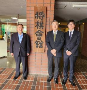 将棋連盟と書かれた看板の前に立つ市長と関係者2名の写真
