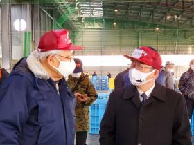 赤い帽子を被った市長が、同じ帽子を被った魚市場の方と会話している写真