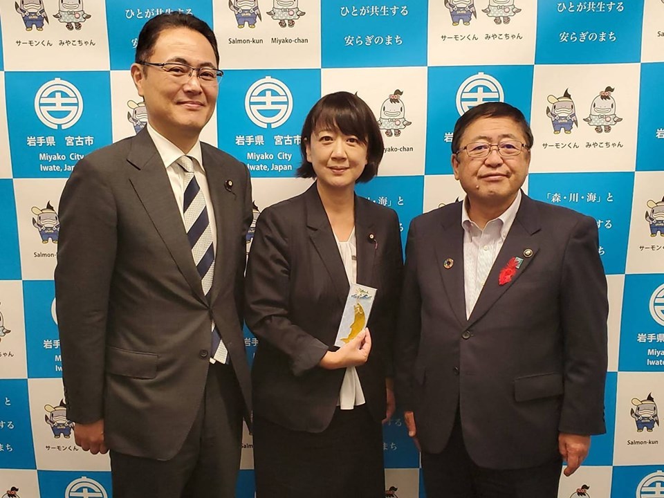 バックパネルの前で、青木愛参議院議員と市長、関係者の男性1名が並んで写る記念写真