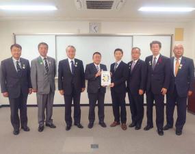 要望書を一緒に持つ市長と関係者の男性を中心に、両側に3名ずつ男性が立って横一列に並んでいる写真