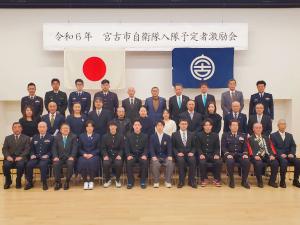 「宮古市自衛隊入隊予定者激励会」の横断幕が飾られたイーストピアみやこで関係者の方々が3列に並んで記念撮影をしている写真