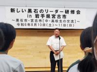 「新しい黒石のリーダー研修会 in 岩手宮古市」の吊り看板があり、マイクスタンドの前に立つ市長の写真