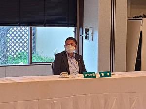白いクロスが引かれた長机の前に座り斜め横に首を向けている様子の市長の写真